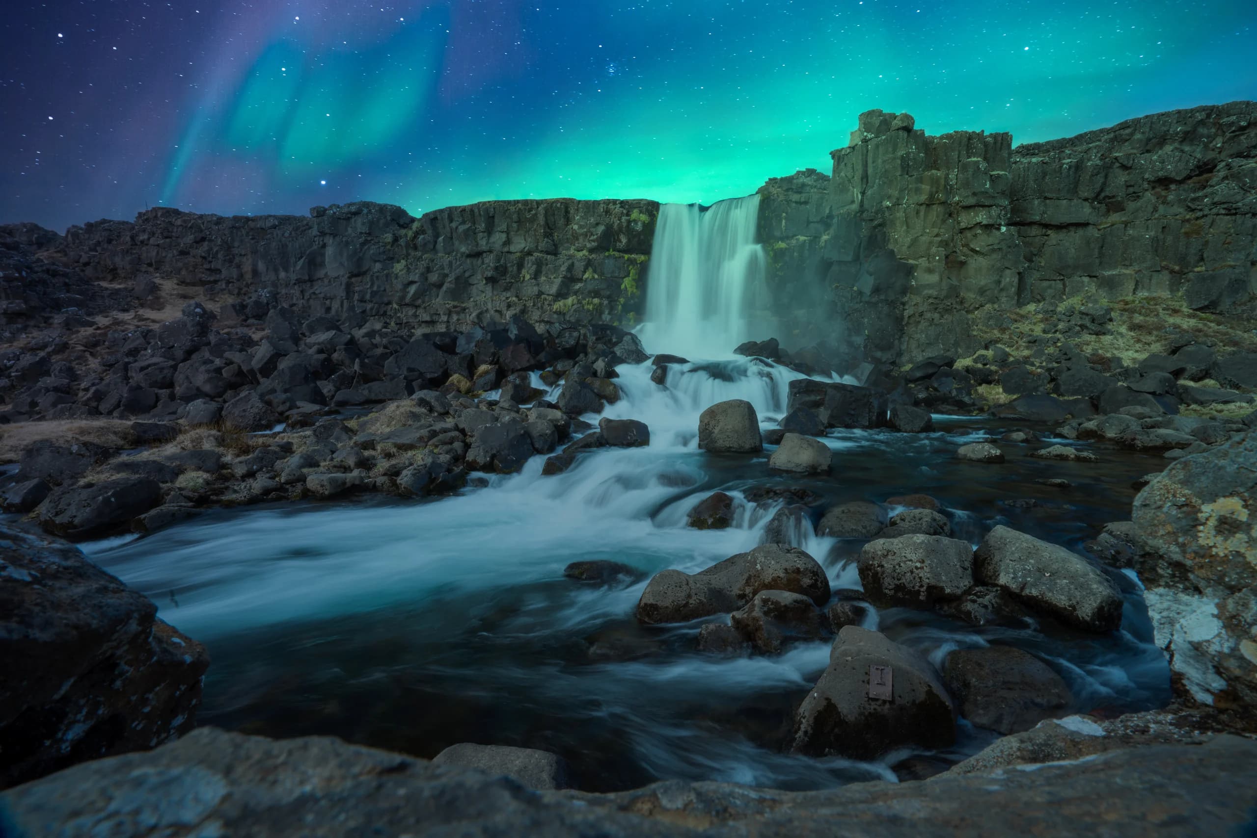 A waterfall under the northern lights in Iceland